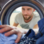man reaching into clothes dryer