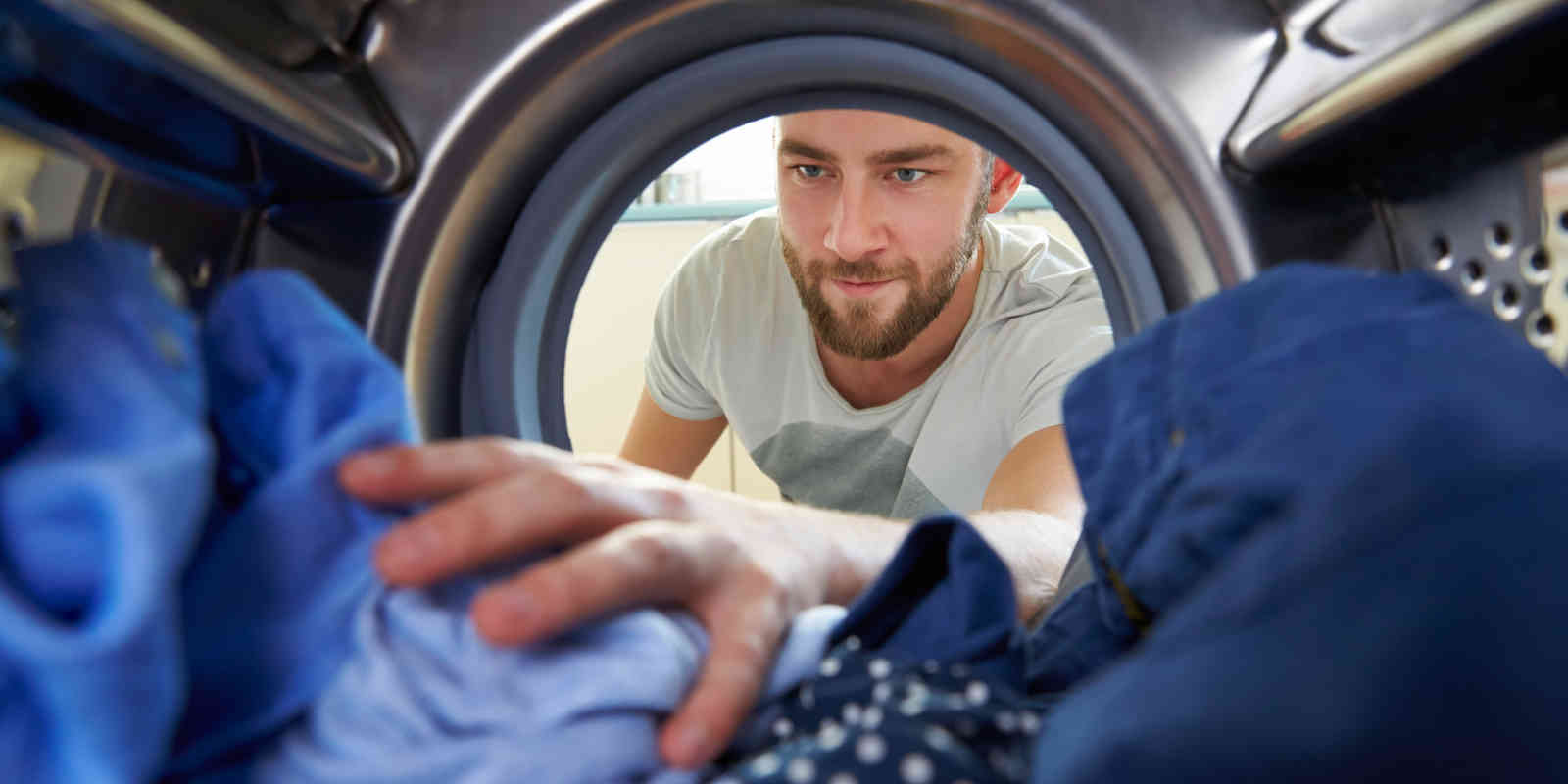 man reaching into clothes dryer