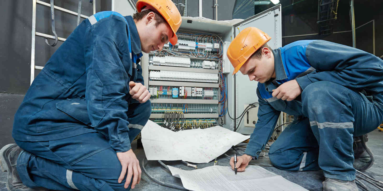 two electrical workers with blueprint