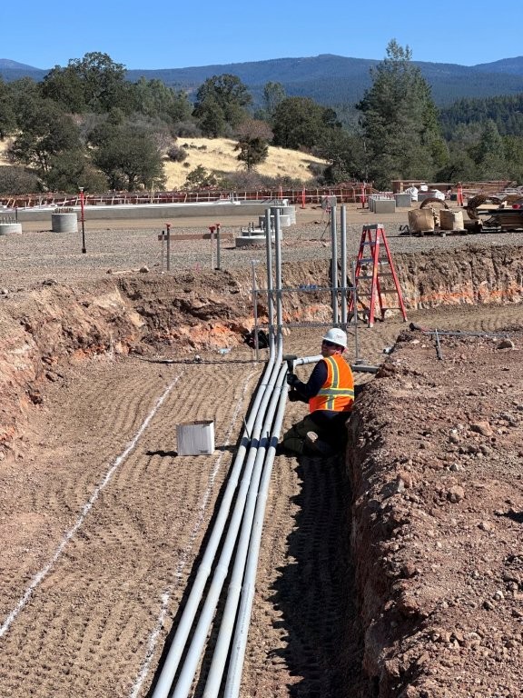 An electrician fitting electrical conduit in a trench