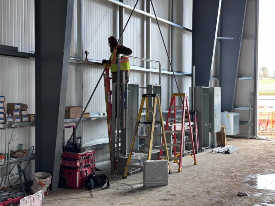 Electrician inspecting power lines on inside wall of industrial facility